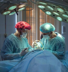 brain surgery with two people in gowns and one on table
